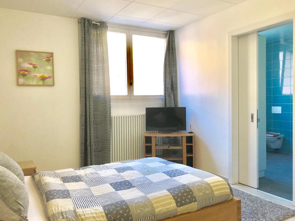 una camera da letto con un letto, una tv e una finestra di Auberge Pour Tous a Vallorbe