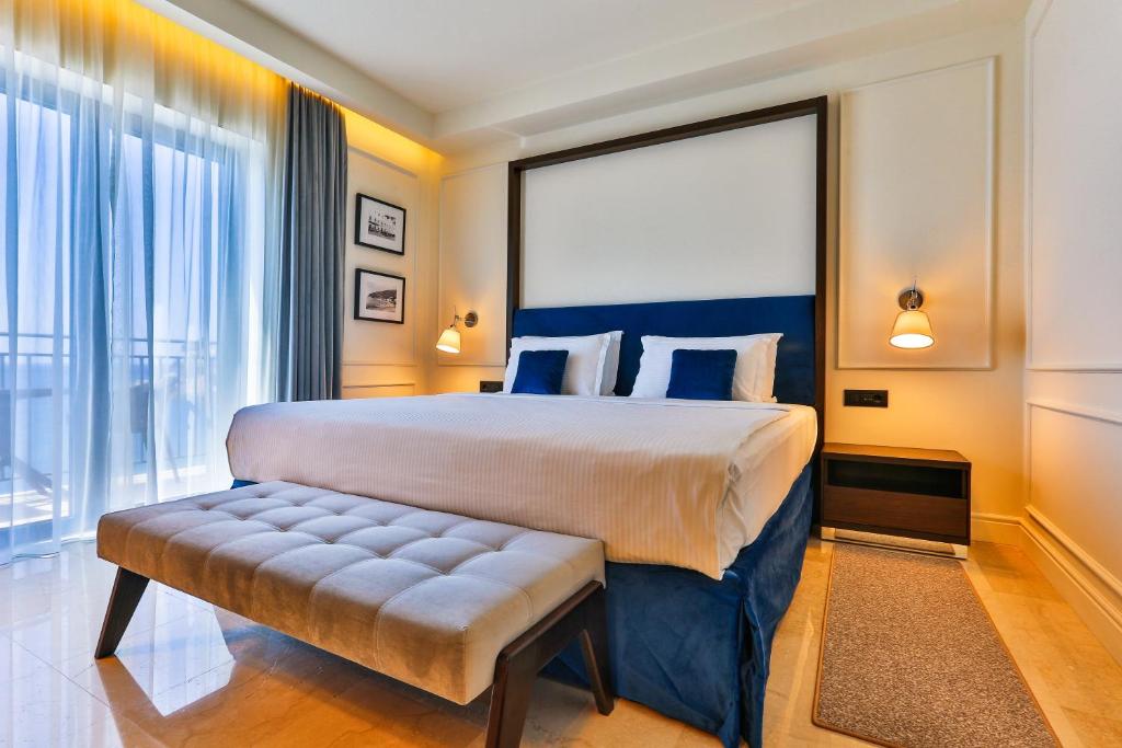 a bedroom with a large bed and a large window at Hotel California by Aycon in Sveti Stefan