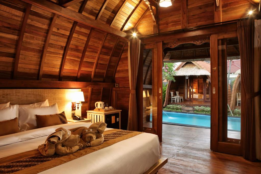 a bedroom with two beds in a room with a pool at Poedja Villa Jimbaran in Jimbaran
