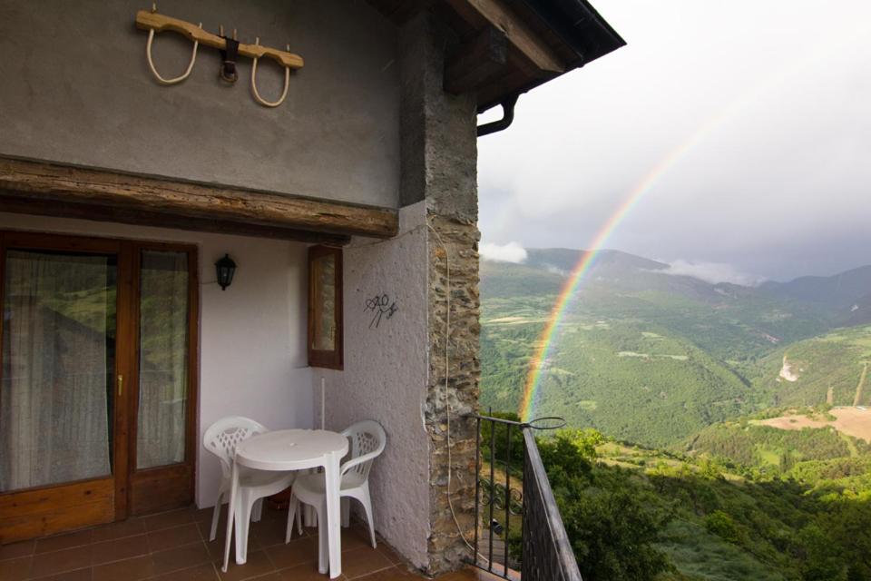 una mesa y sillas en un balcón con arco iris en Casa Rural Baró, en Tornafort