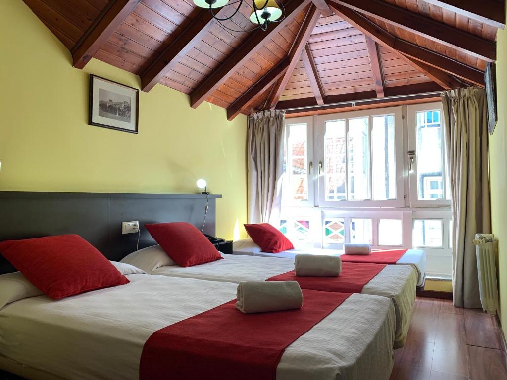 2 Betten mit roten Kissen in einem Hotelzimmer in der Unterkunft Hostal Hotil Coruña Centro in A Coruña
