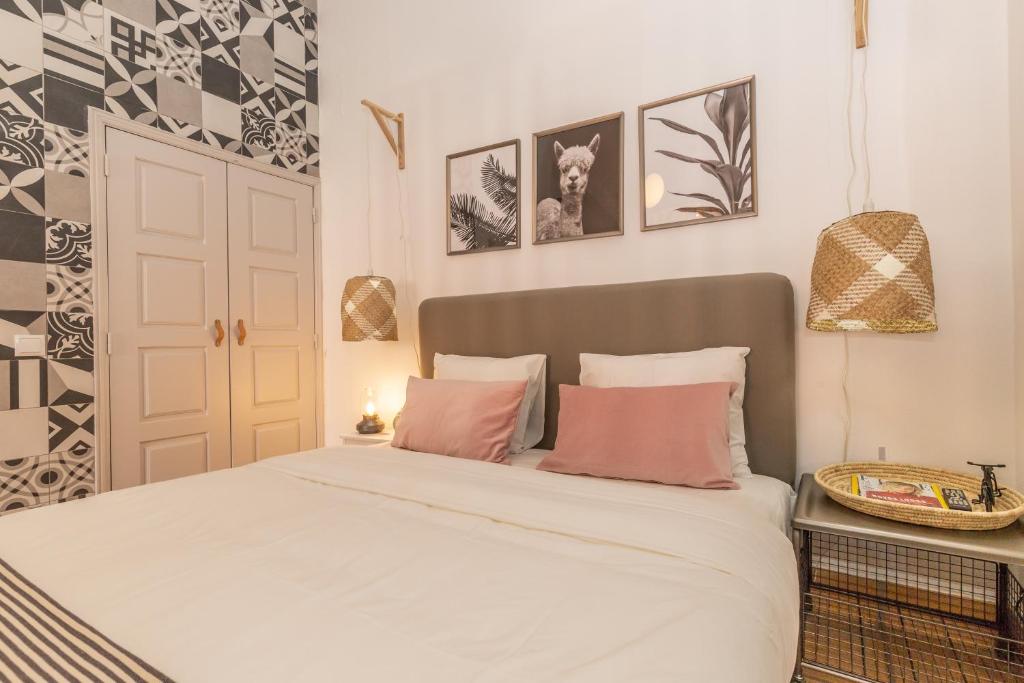a bedroom with a bed with white sheets and pink pillows at FARO DOWNTOWN STUDIOS in Faro