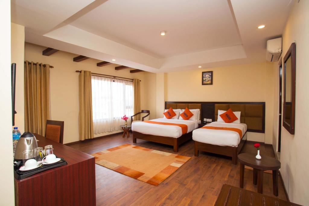 een hotelkamer met 2 bedden en een televisie bij Hotel Jay Suites in Kathmandu