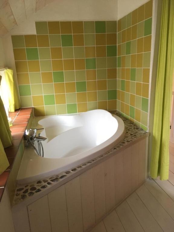 a bath tub in a bathroom with green and orange tiles at Gîte les Mineurs in Zottegem