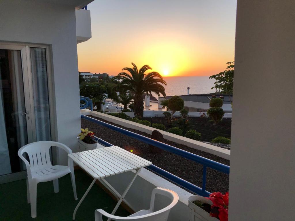 einen Tisch und Stühle auf einem Balkon mit Blick auf den Sonnenuntergang in der Unterkunft The Pradise of Ana Vemar Exclusive Apartament in Playa Paraiso
