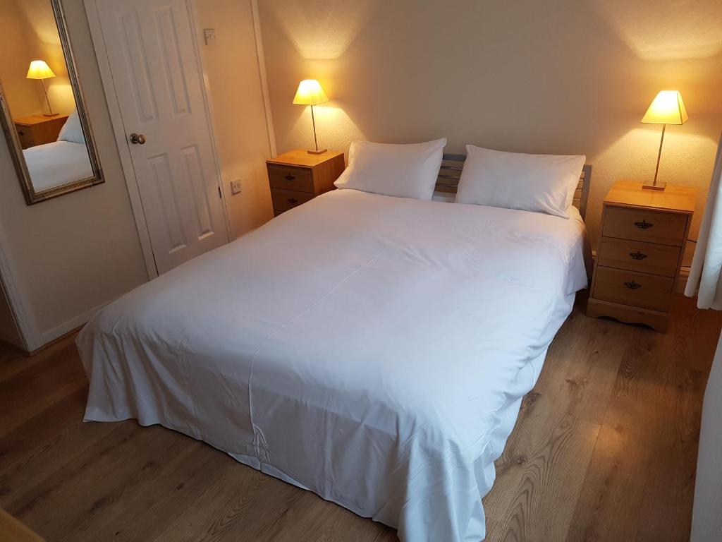 a bedroom with a large white bed with two lamps at Boscombe Reef Hotel in Bournemouth