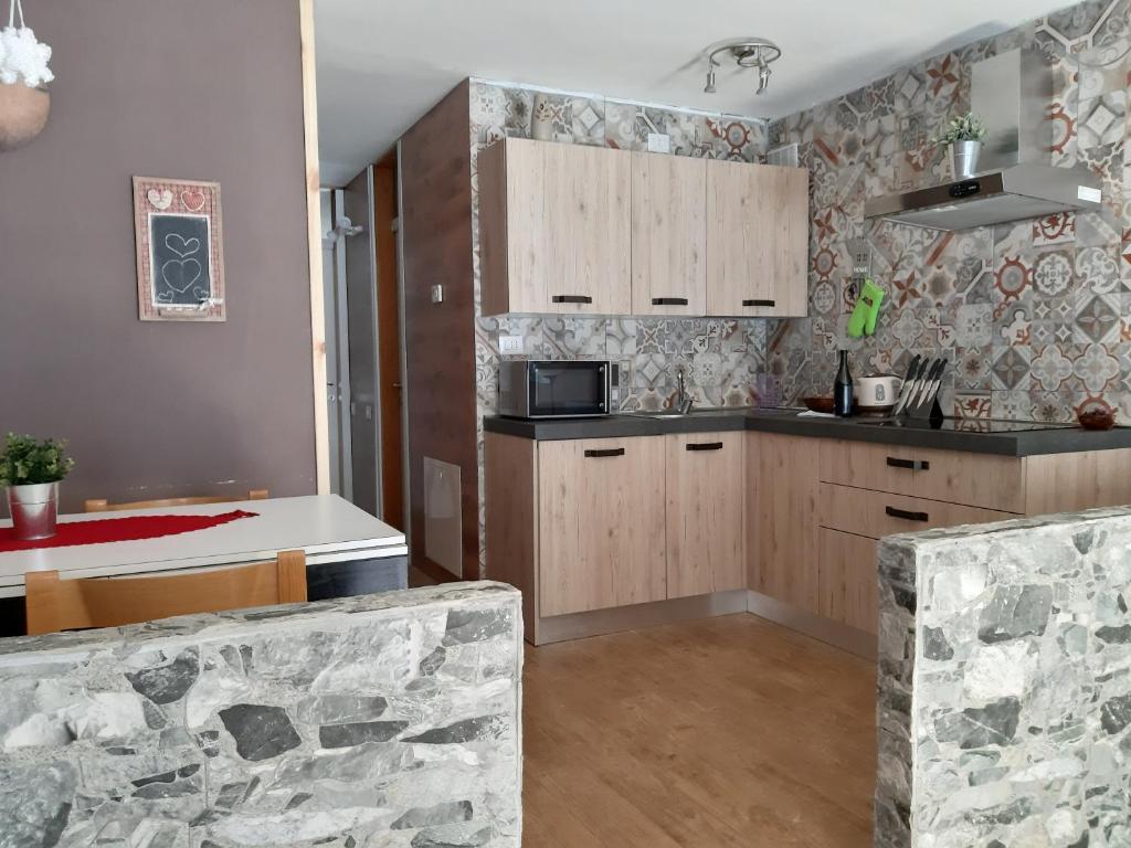 a kitchen with wooden cabinets and a stone wall at Sul cucuzzolo in Marilleva