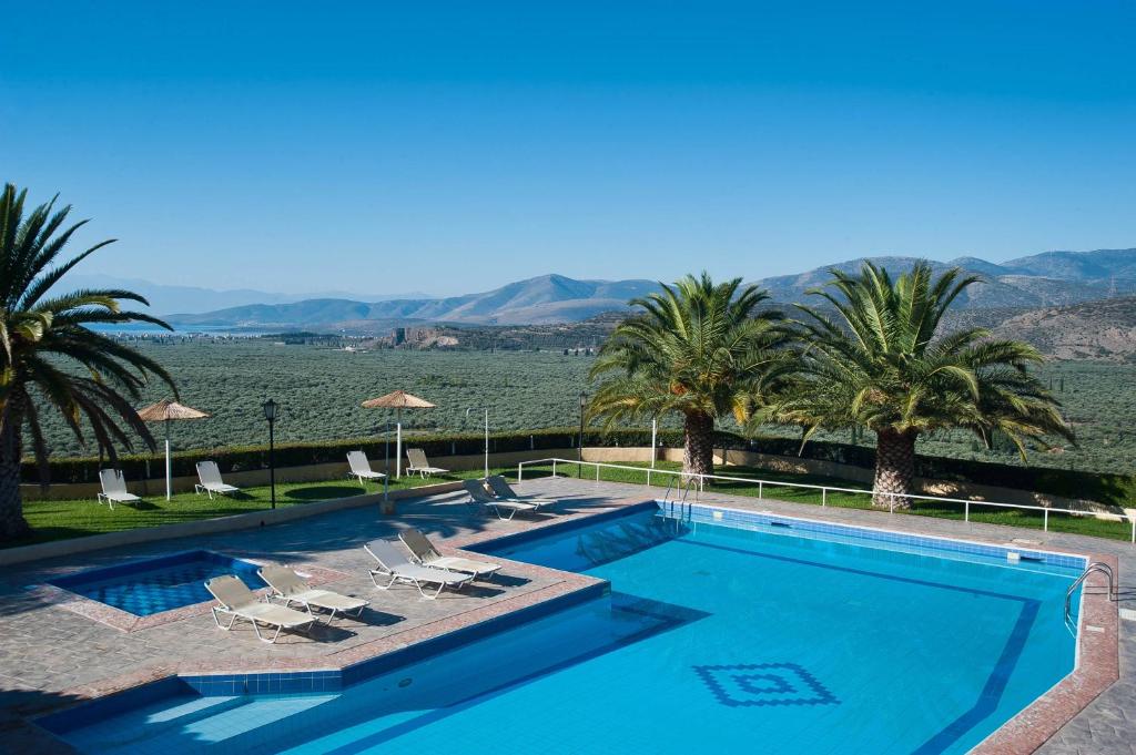 a swimming pool with palm trees and a view of the desert at Chrissa Camping Rooms & Bungalows in Delfoi