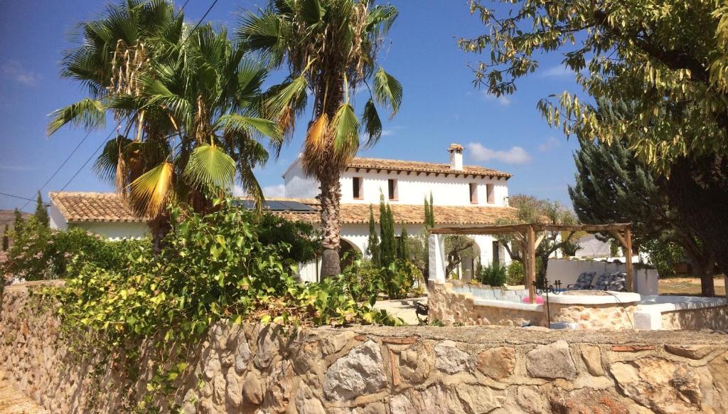 a white house with palm trees and a stone wall at Buena Idea - Adults Only in Jalón