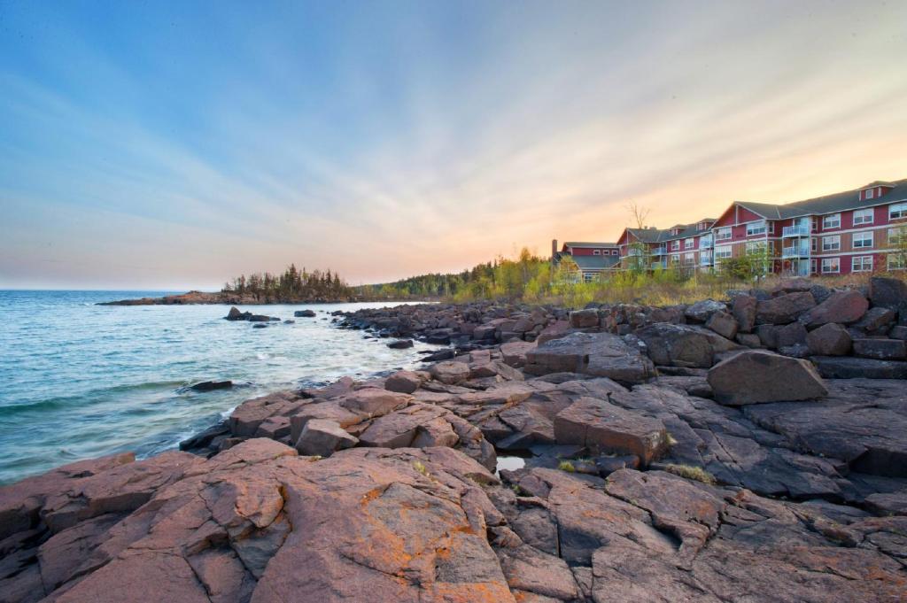 a rocky shoreline with buildings and the ocean at Cove Point Lodge in Beaver Bay