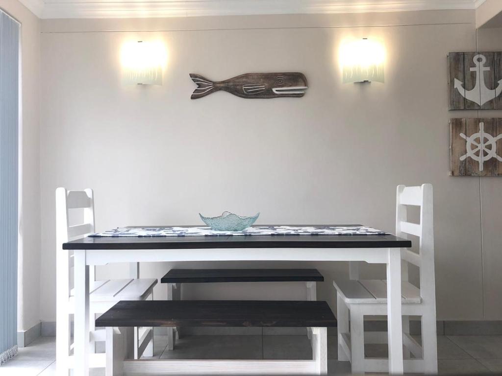 a dining room table with two chairs and a fish on the wall at Seaside Place in Struisbaai