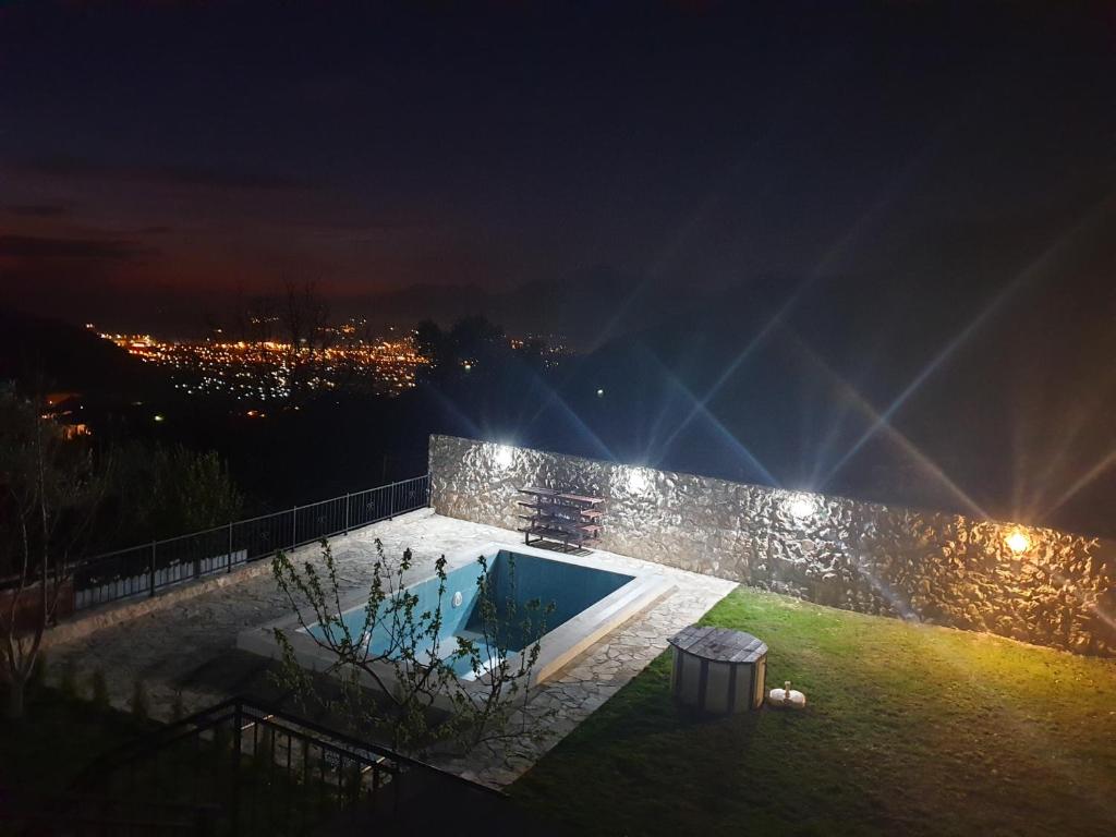 a swimming pool at night with a city lights at Apartman Nikocevic in Dobra Voda