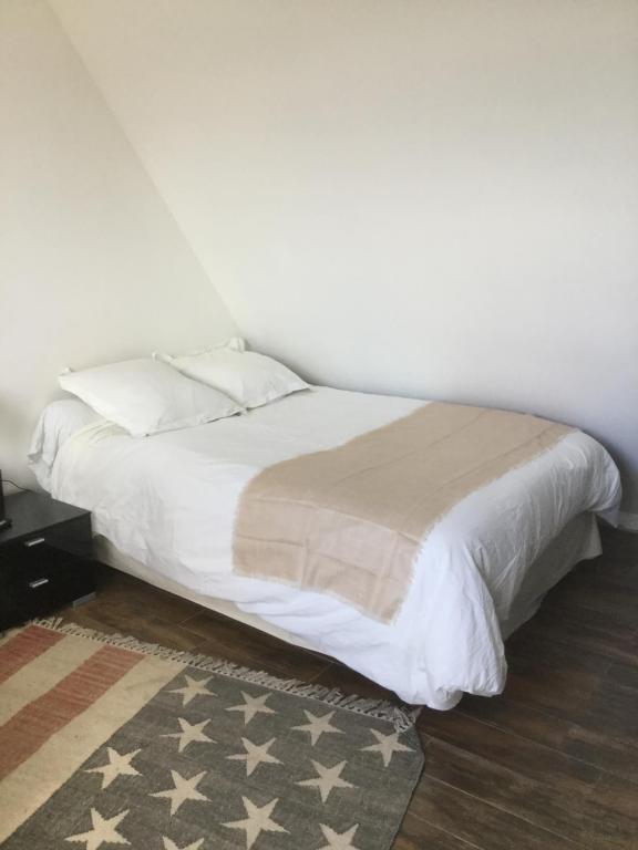 a bed with white sheets and pillows in a bedroom at Maison de Sandrine in Jumeauville