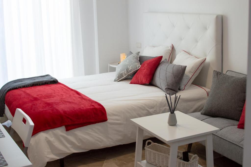 a bedroom with a white bed and a red blanket at Apartamentos Océanos in Málaga