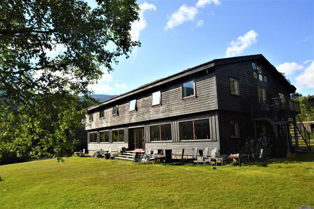 une grande maison noire sur un champ herbeux dans l'établissement Voss Lodge Rongastovo, à Vossevangen