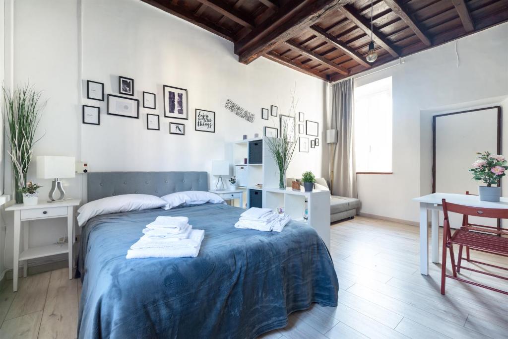 a white bedroom with a blue bed and a table at Cozy studio Campo de Fiori in Rome