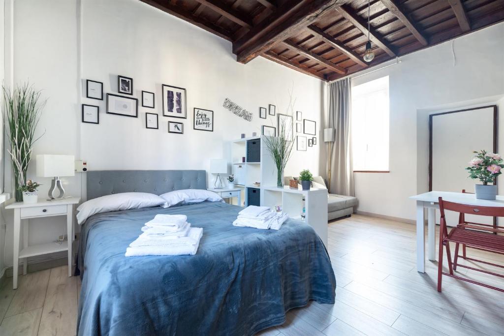 biała sypialnia z niebieskim łóżkiem i stołem w obiekcie Cozy studio Campo de Fiori w Rzymie