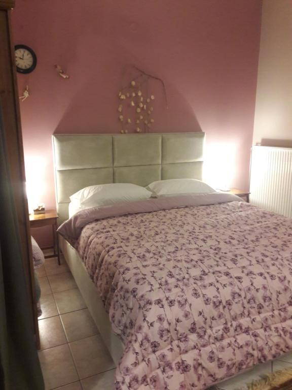 a bedroom with a large bed with a pink wall at 4epoxes in Tinos