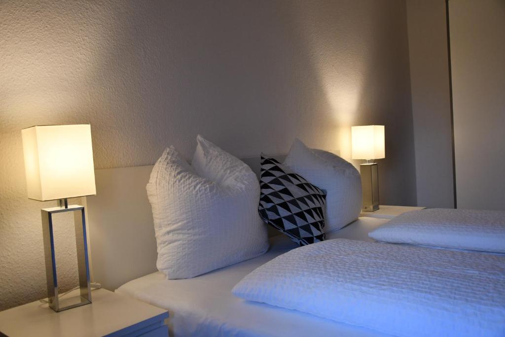 una camera con 2 letti con cuscini bianchi e 2 lampade di Vicky´s Ferienwohnung a Flensburgo