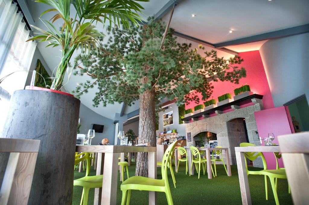 a restaurant with green chairs and a tree in the middle at Les Portes d'Apcher in Saint-Chély-dʼApcher