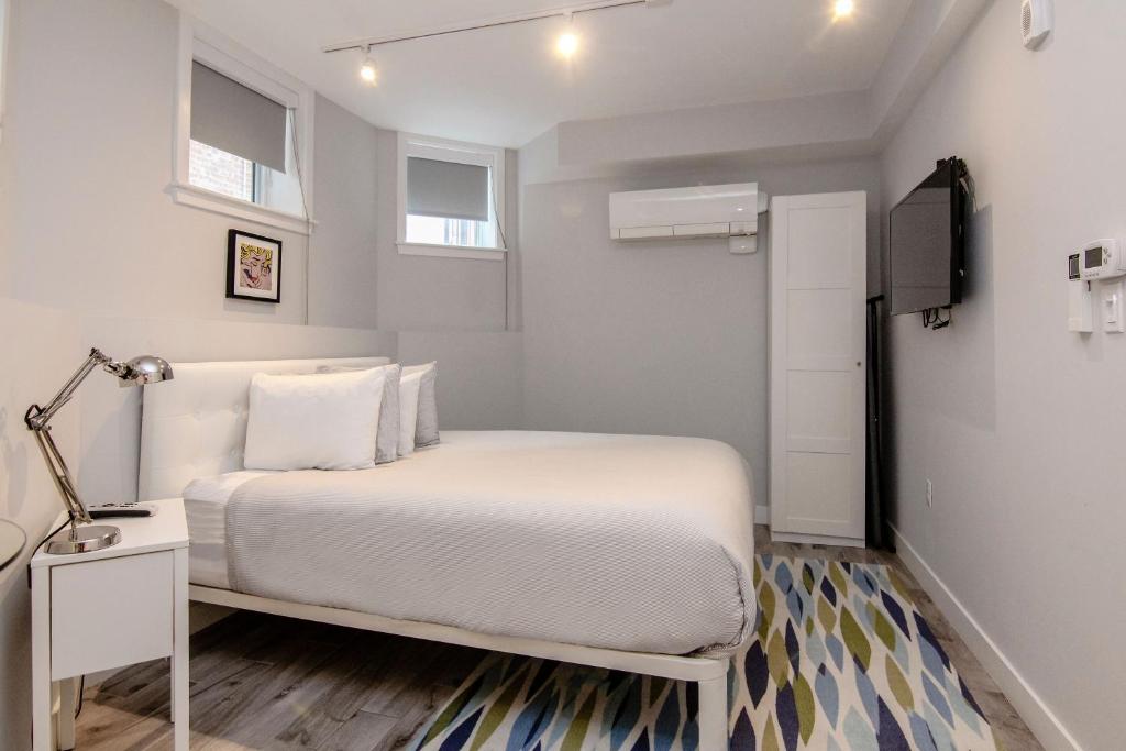 um quarto com uma cama branca com um candeeiro e uma televisão em A Stylish Stay w/ a Queen Bed, Heated Floors.. #3 em Brookline