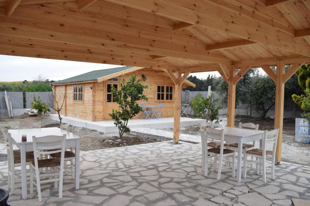 a wooden pavilion with white chairs and a house at Cyprus Glamping Park in Ayios Theodhoros