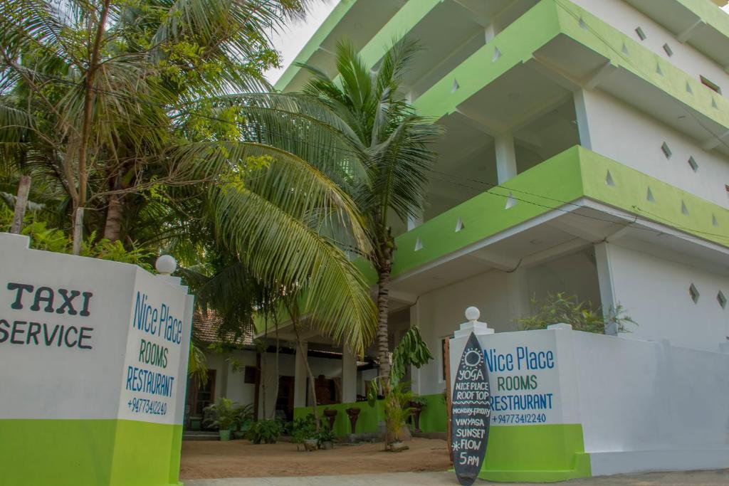 un edificio verde e bianco con cartelli di fronte di Nice Place Beach Hotel ad Arugam