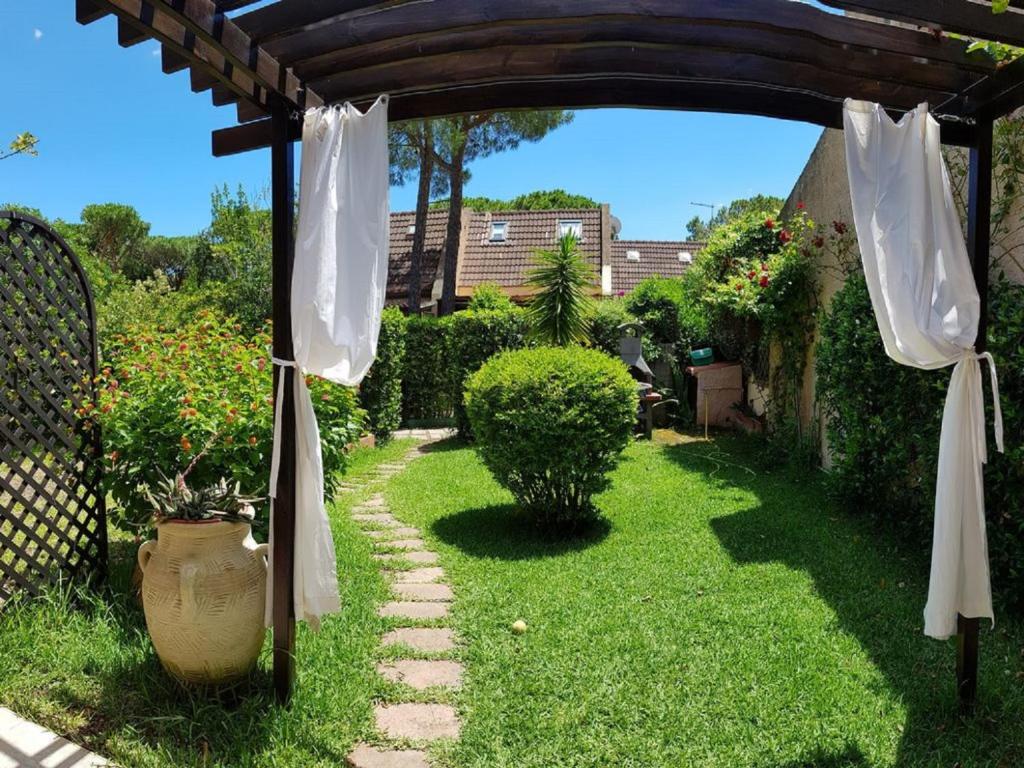 an arch over a yard with a vase on the grass at Villetta con giardino immersa nel verde a 150mt dal mare in Pula