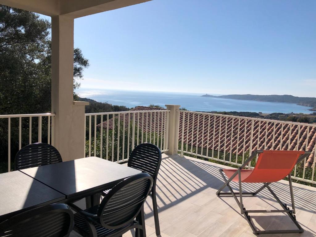 una mesa y sillas en un balcón con vistas al océano en Residence Castugna, en Cargèse