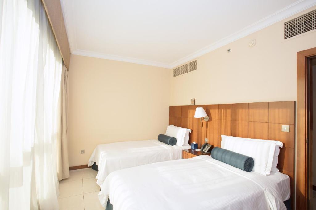 a hotel room with two beds with white sheets at Al Rawda Arjaan by Rotana, Abu Dhabi in Abu Dhabi