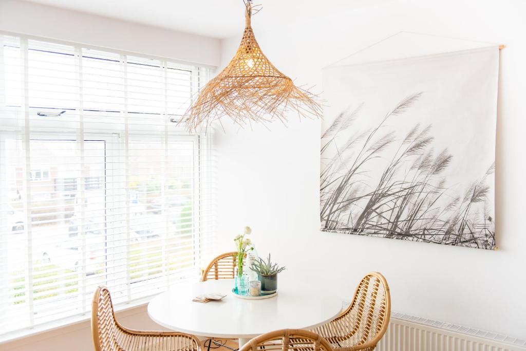 Un comedor con una mesa y sillas blancas. en Appartement Zuyd, en Zandvoort