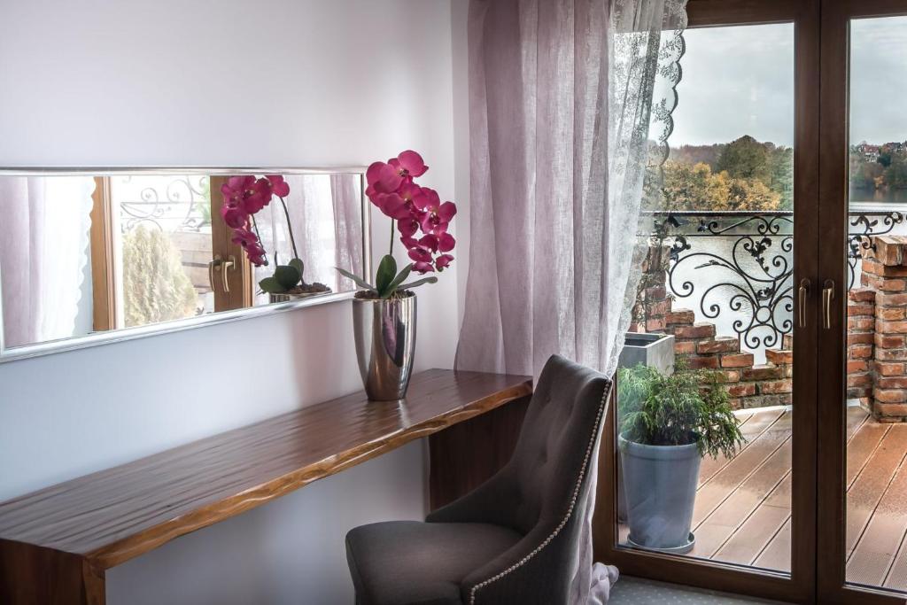 Wooden desk with pink orchid and upholstered chair beside balcony doors overlooking a lake