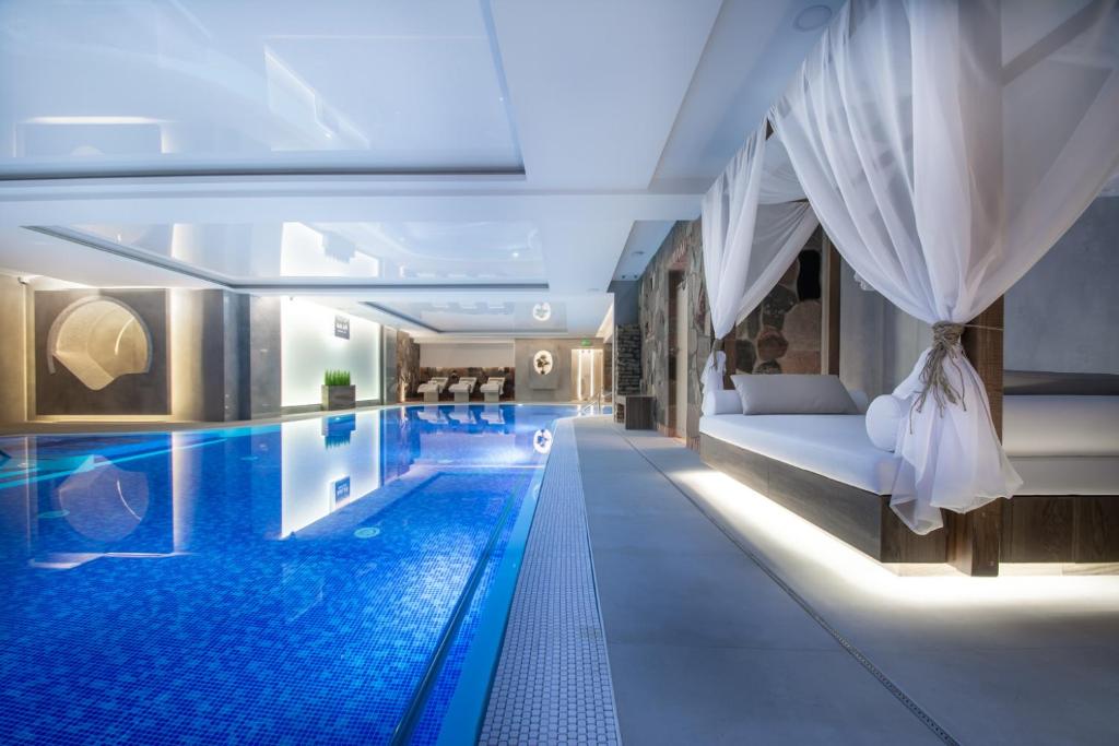 a hotel swimming pool with a bed and a tub at Adler Medical SPA Kaszuby in Stężyca