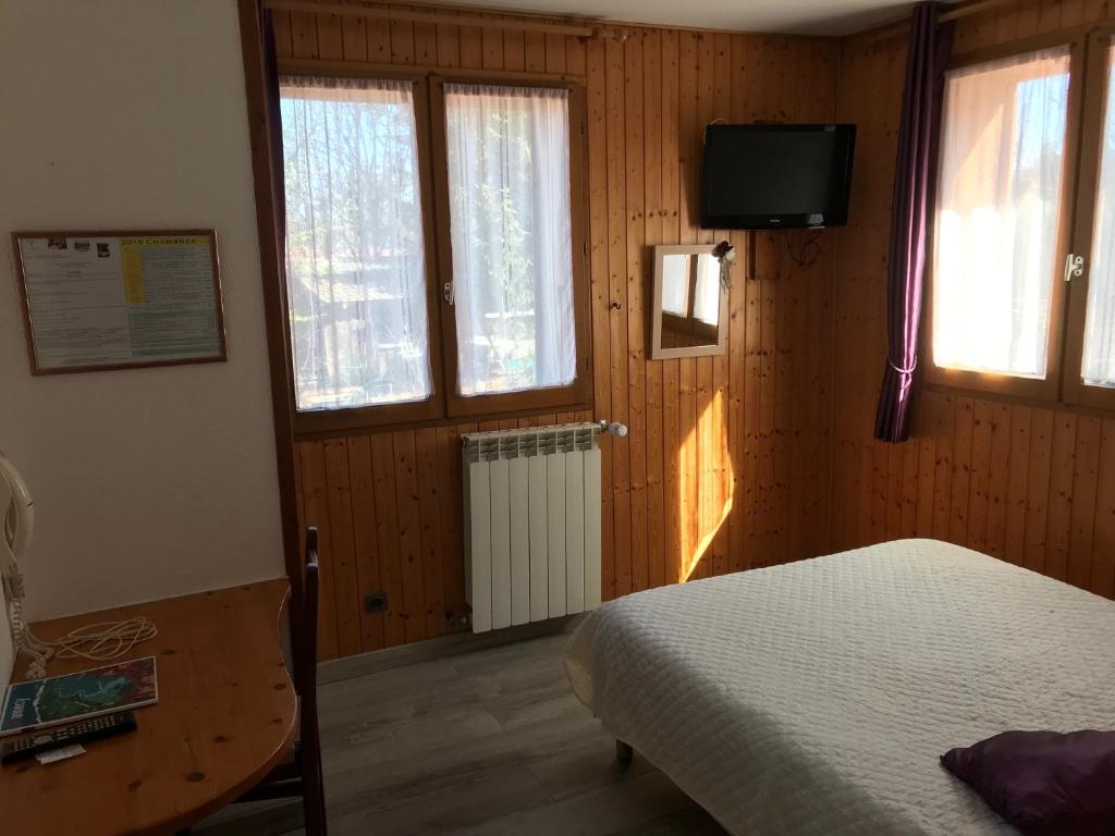 Schlafzimmer mit einem Bett, einem TV und Fenstern in der Unterkunft Domaine de la Caille in La Balme-de-Sillingy