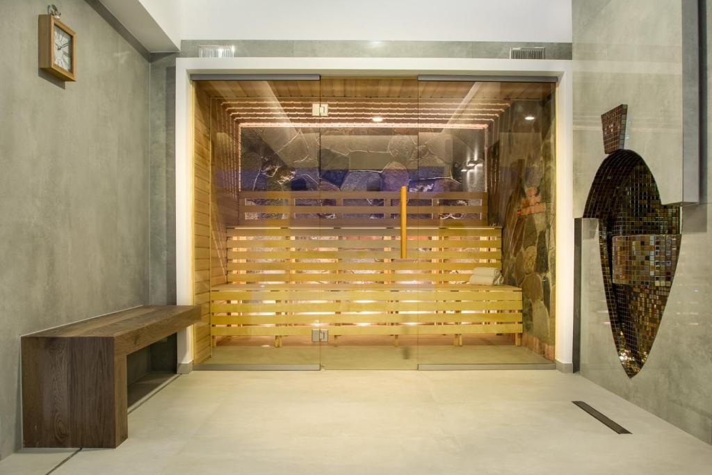 Glass-fronted wooden sauna with tiered benches, warm interior lighting, and seating bench outside.