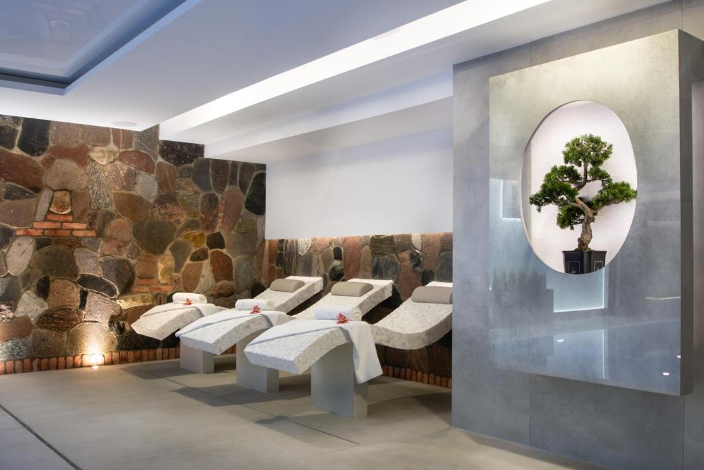 Three stone reclining spa loungers against a rustic rock wall, serene bonsai display in alcove.