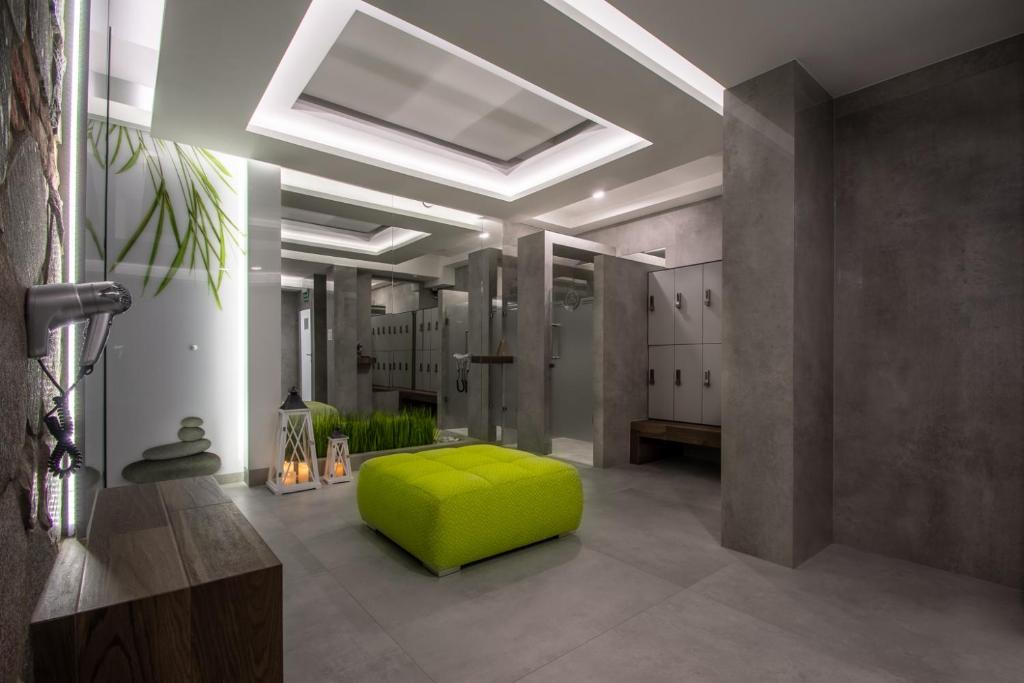 Modern changing room with bright ceiling lights, green pouf, lockers, and decorative lanterns.