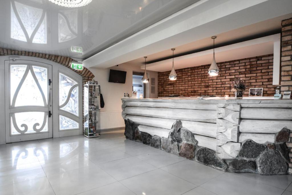Bright reception area with white log-style front desk, stone base, pendant lights, tiled floor.
