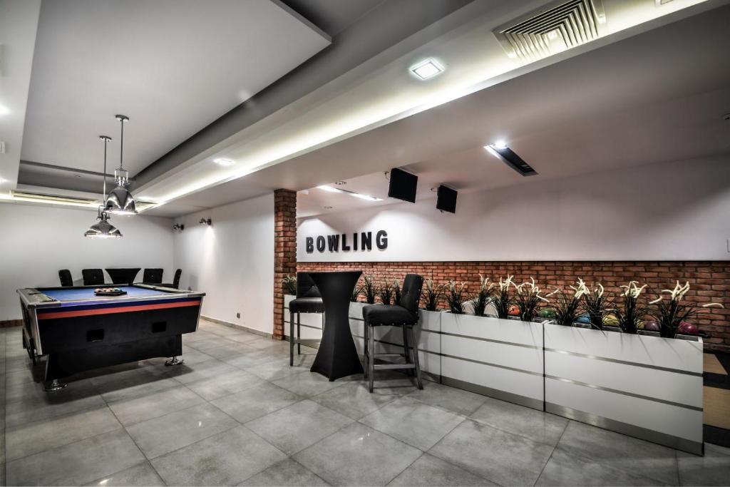 Recreation room with pool table, high seats, bowling sign, and brick-accented wall