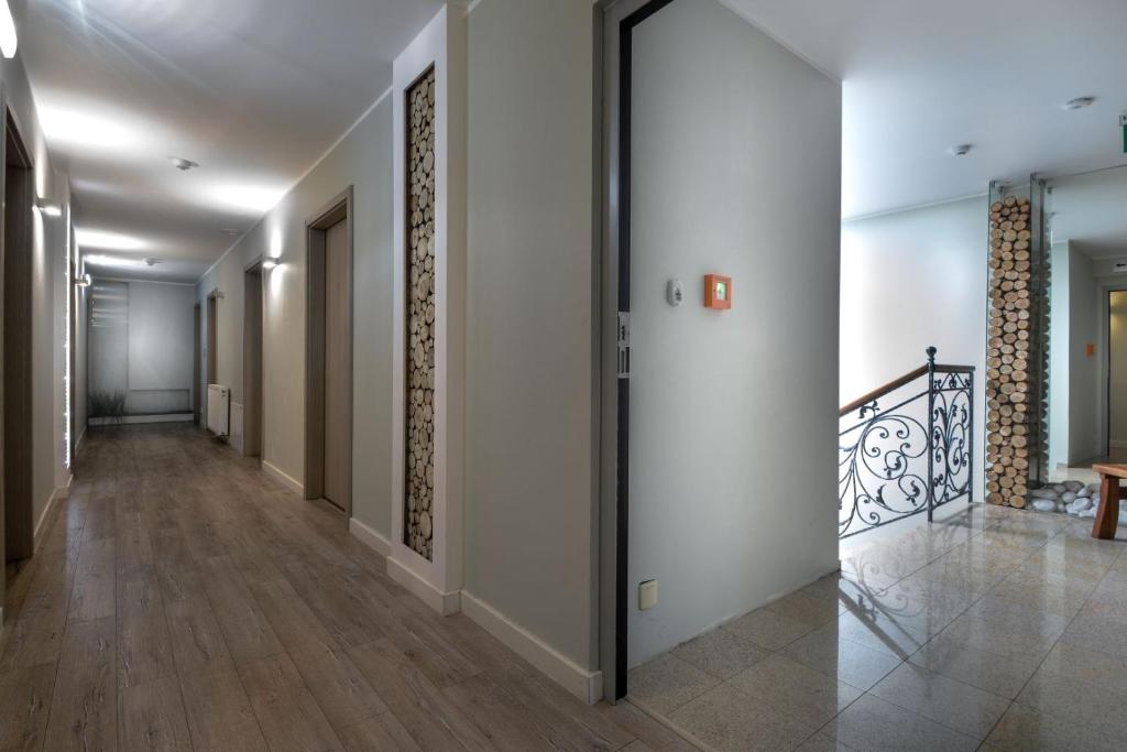 Quiet hotel hallway with wood-log decorative panels, doors, and ornate staircase railing
