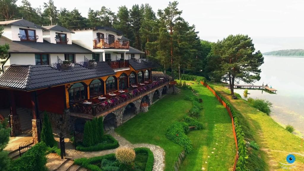Lakeside hotel with terrace dining, manicured lawn sloping to pier and surrounding trees.