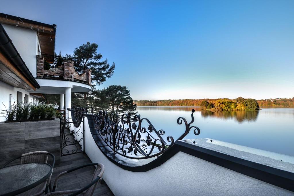 Curved balcony with ornate wrought-iron railing overlooking calm lake and distant island.