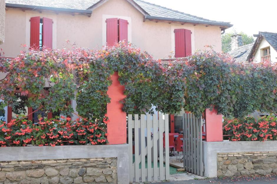 une maison avec des fleurs devant une clôture dans l'établissement Hôtel Les Vignes Rouges, à Ispagnac