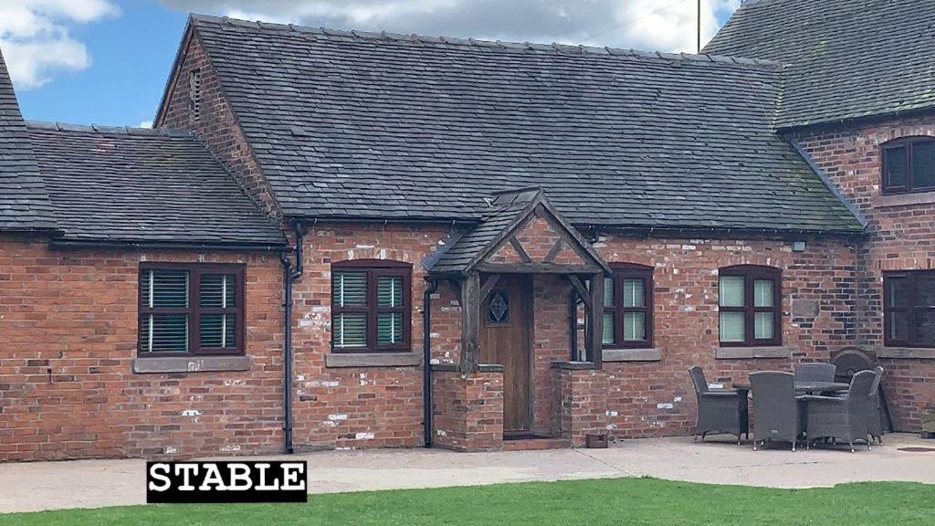 a brick house with a table and chairs in front of it at Domvilles Farm self catering Courtyard Stable in Alsager