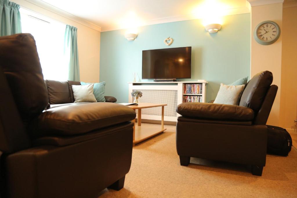 a living room with two chairs and a flat screen tv at Seashells in Newquay