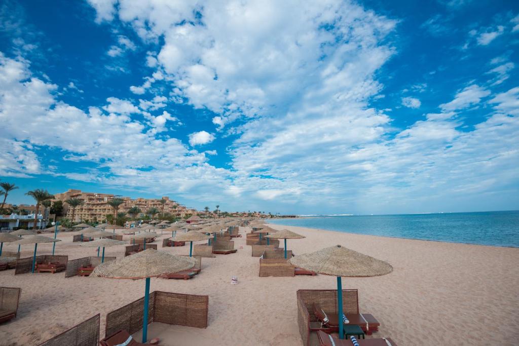 a beach with umbrellas and chairs and the ocean at Shams Safaga Resort in Hurghada