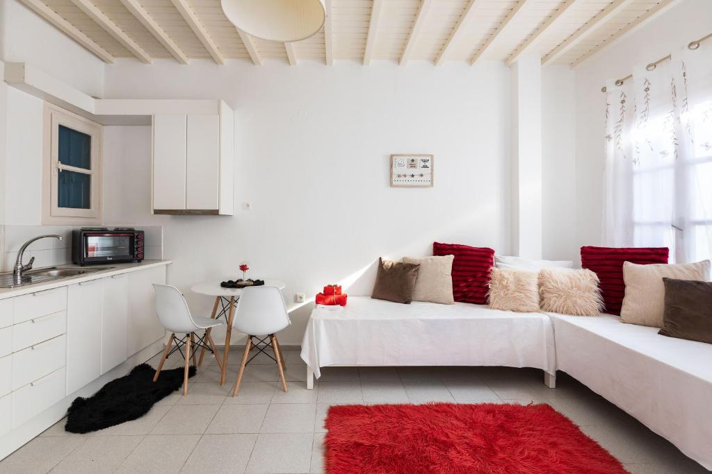 a white living room with a white couch and a red rug at Izabela's House Mykonos Town in Megali Ammos