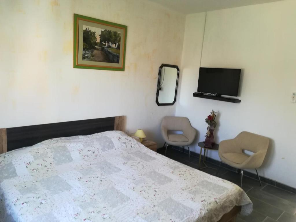 a bedroom with a bed and two chairs and a tv at Guesthouse Porec in Poreč