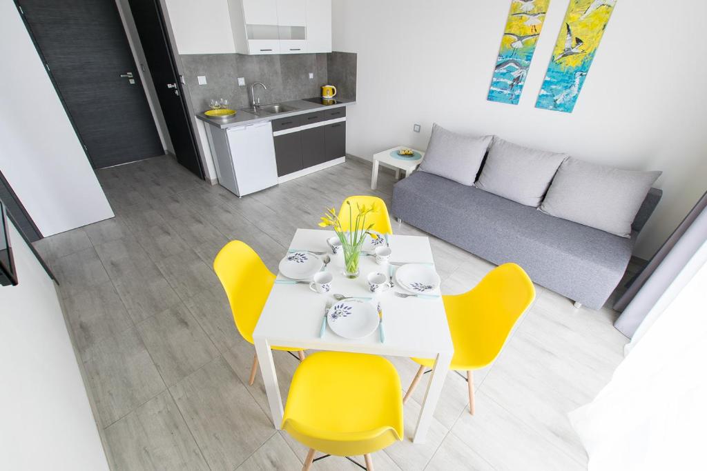 a dining room with a white table and yellow chairs at Laba in Jastrzębia Góra