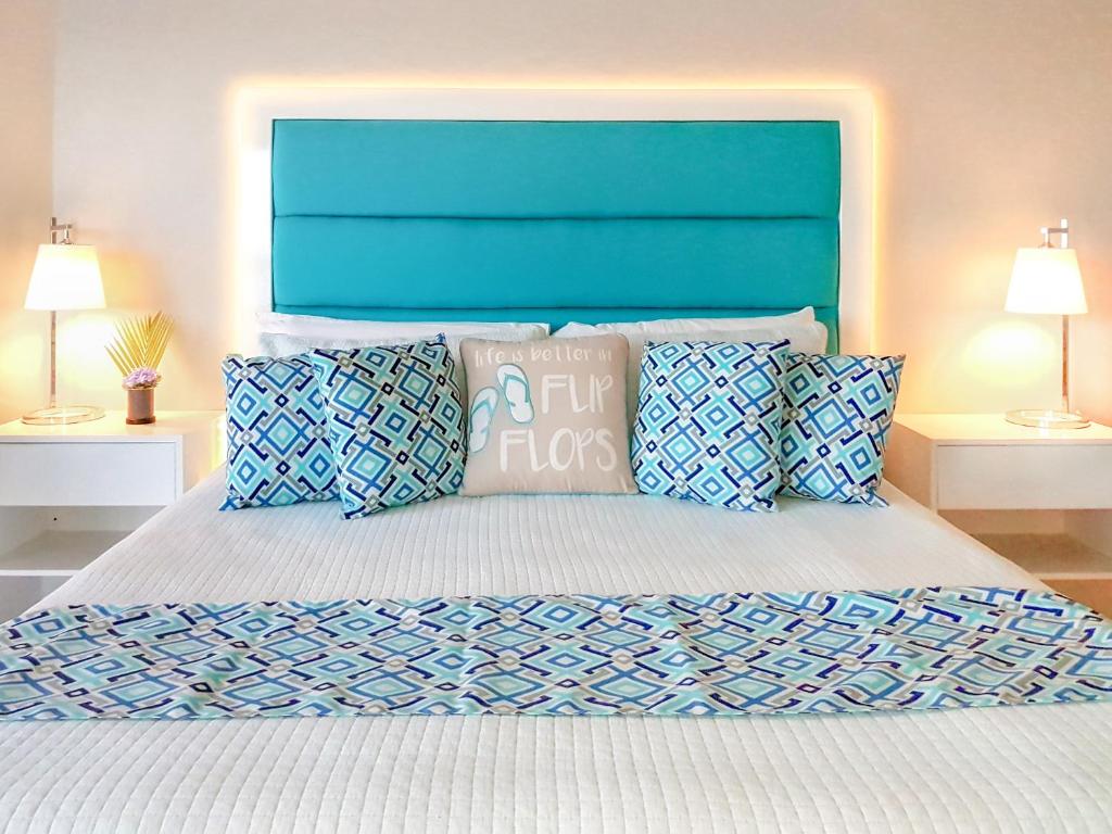 a bedroom with a bed with a blue headboard and pillows at Luxe Beach Resort in Discovery Bay